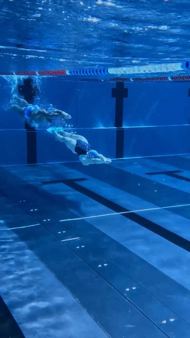 Два пловца плывут под водой параллельно по дорожкам